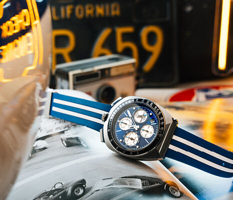 Bulova Shelby Racing Chronograph watch with blue and white strap photographed on an open magazine featuring classic racing cars.